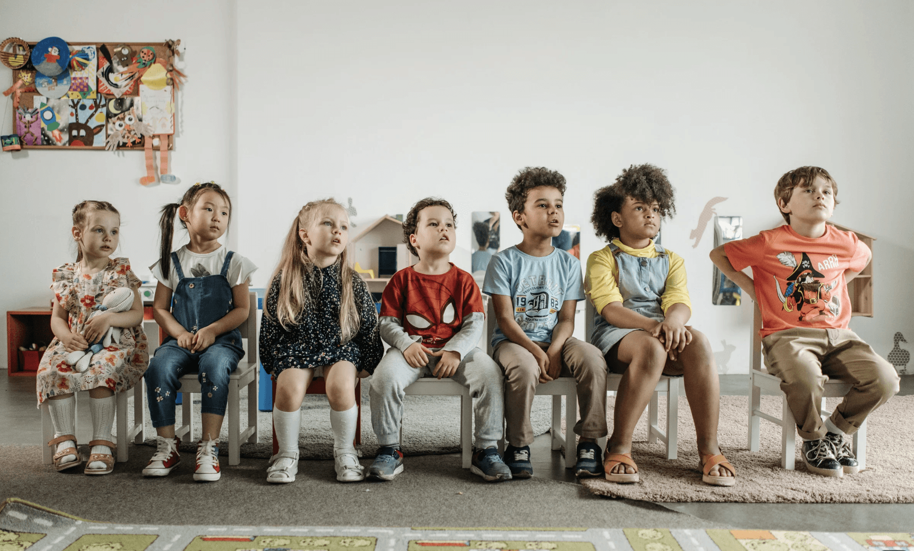 A group of children sitting in a single file listening to a teacher's instructions